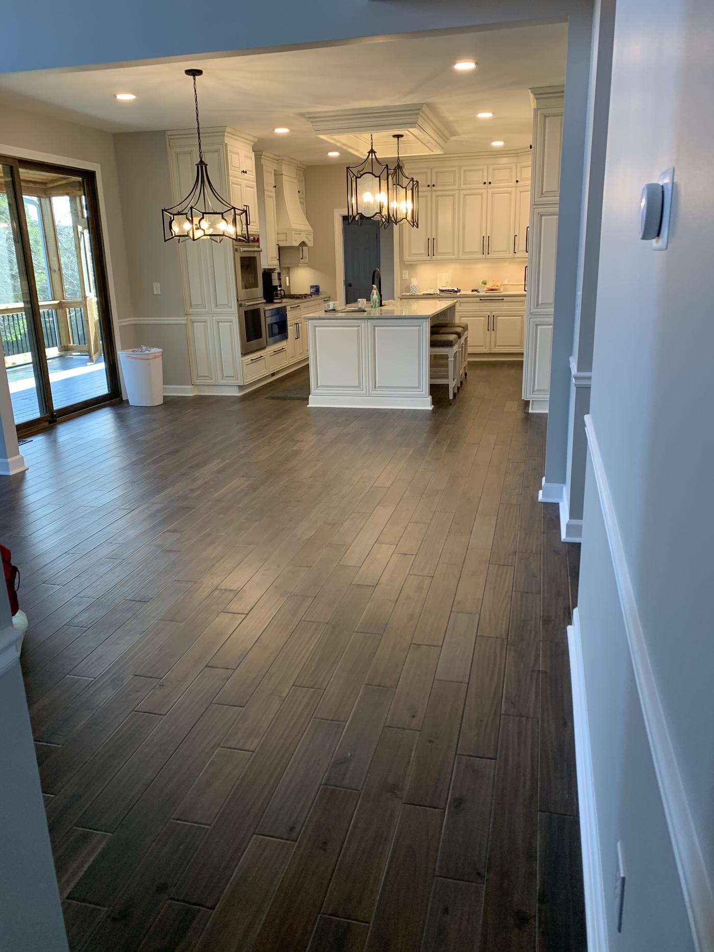Open floor plan with hardwood floors leading to a white kitchen